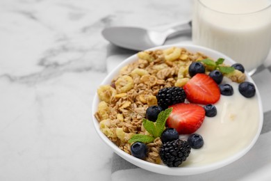 Photo of Tasty oatmeal, yogurt and fresh berries in bowl on white marble table, closeup with space for text. Healthy breakfast