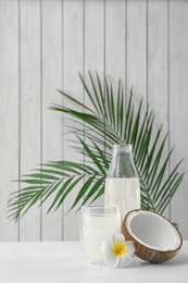 Composition with bottle and glass of coconut water on white wooden table