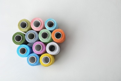 Color sewing threads on white background, top view