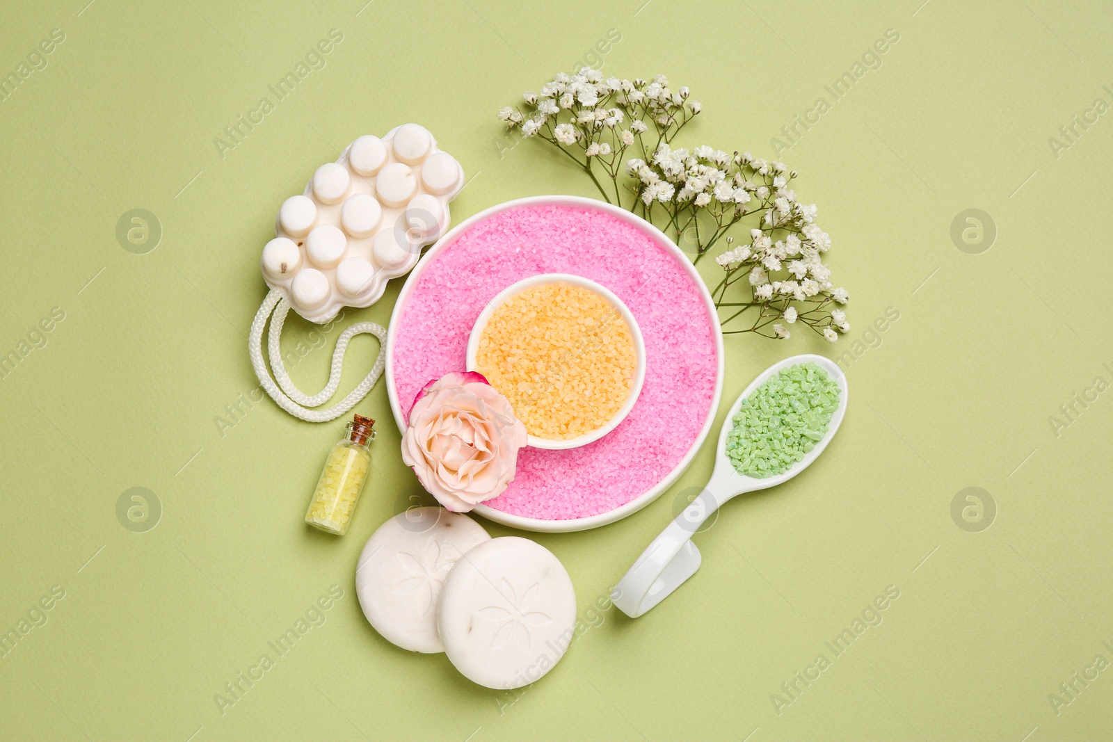 Photo of Sea salt, soap bars and beautiful flowers on olive background, flat lay