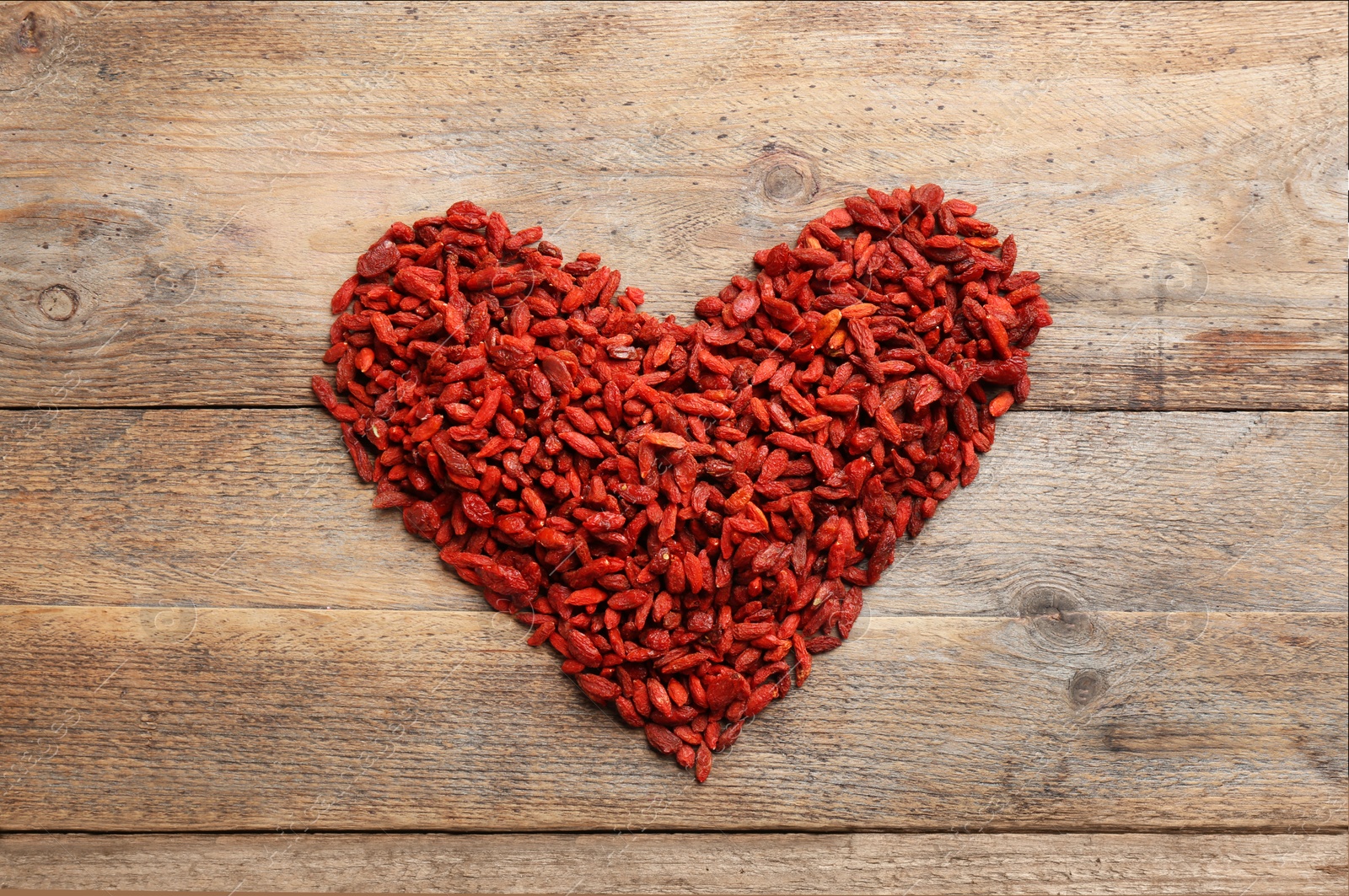 Photo of Heart made of dried goji berries on wooden table, top view. Healthy superfood