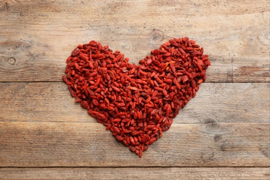 Photo of Heart made of dried goji berries on wooden table, top view. Healthy superfood