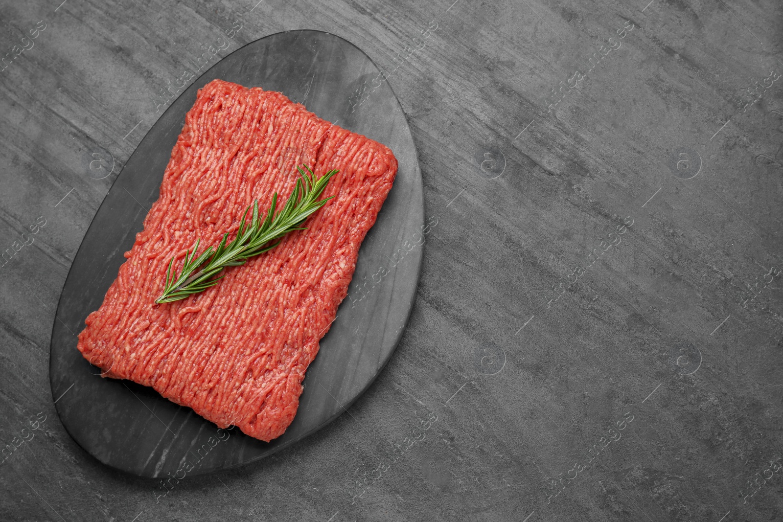 Photo of Raw fresh minced meat with rosemary on black wooden table, top view. Space for text