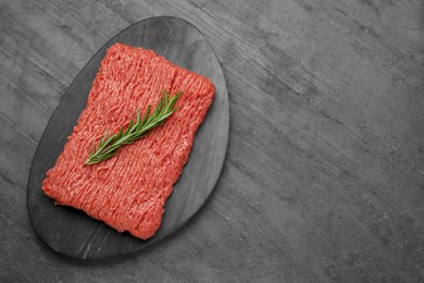 Raw fresh minced meat with rosemary on black wooden table, top view. Space for text