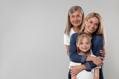 Photo of Three generations. Happy grandmother, her daughter and granddaughter on light gray background, space for text