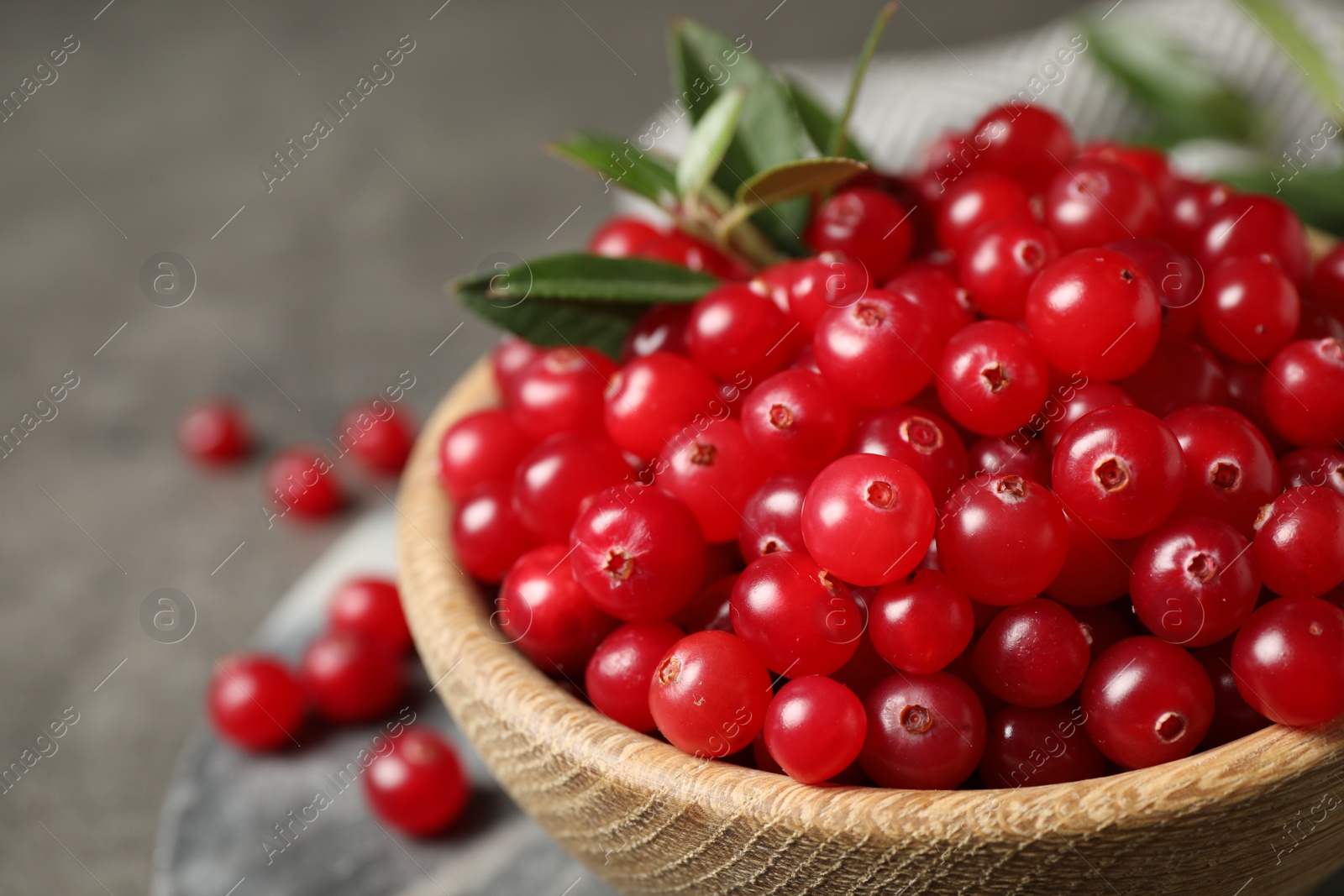 Photo of Bowl with tasty ripe cranberries on table, closeup