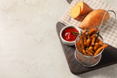 Photo of Sweet potato fries and ketchup on light grey table, above view. Space for text