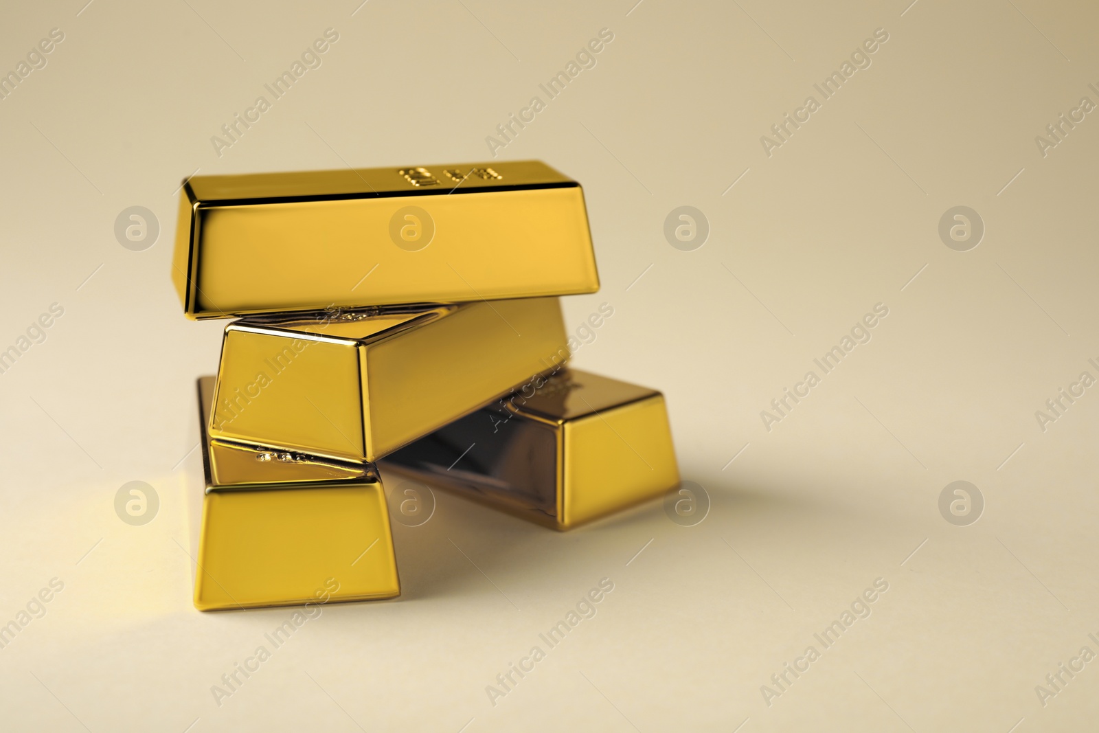 Photo of Many shiny gold bars on beige background. Space for text