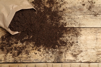 Photo of Paper bag and soil on wooden table, top view with space for text. Gardening season