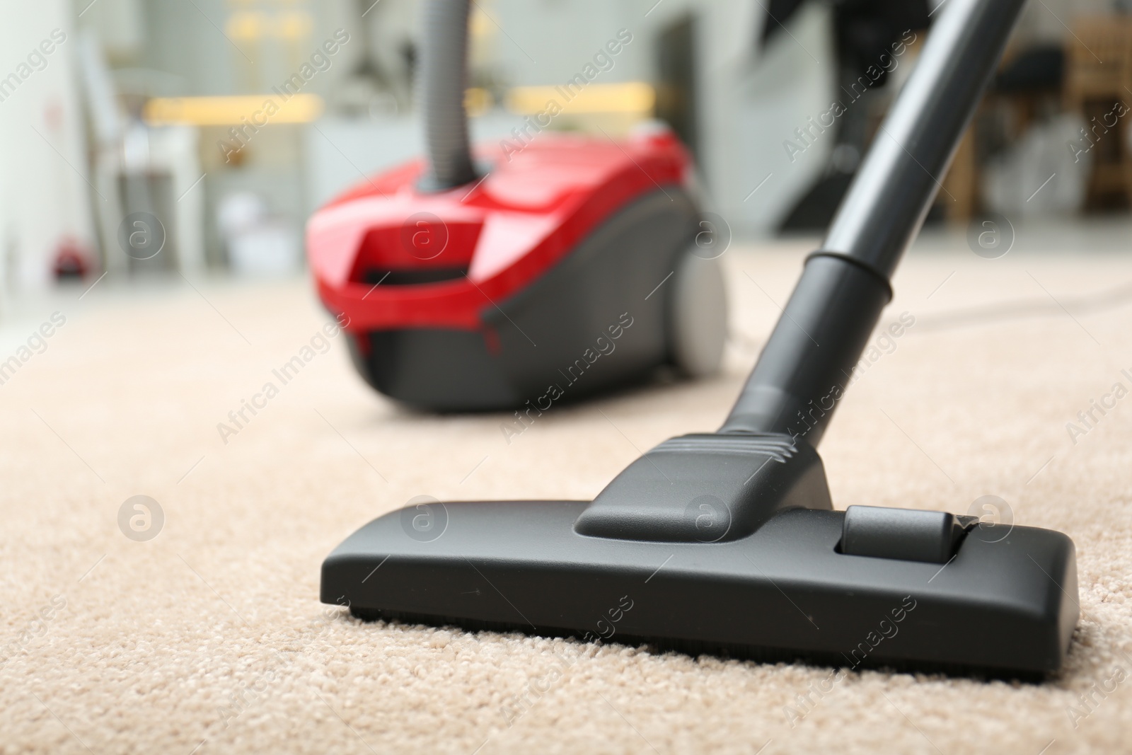 Photo of Removing dirt from carpet with vacuum cleaner indoors, closeup