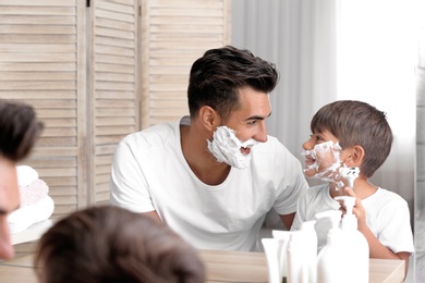 Father and son having fun while shaving in bathroom