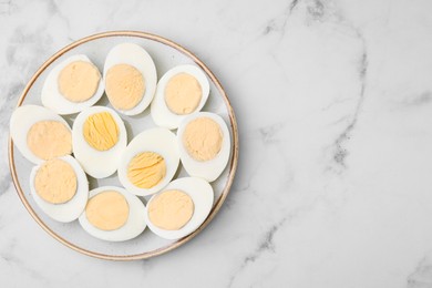 Photo of Fresh hard boiled eggs on white marble table, top view. Space for text