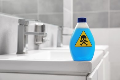 Photo of Bottle of toxic household chemical with warning sign in bathroom, space for text