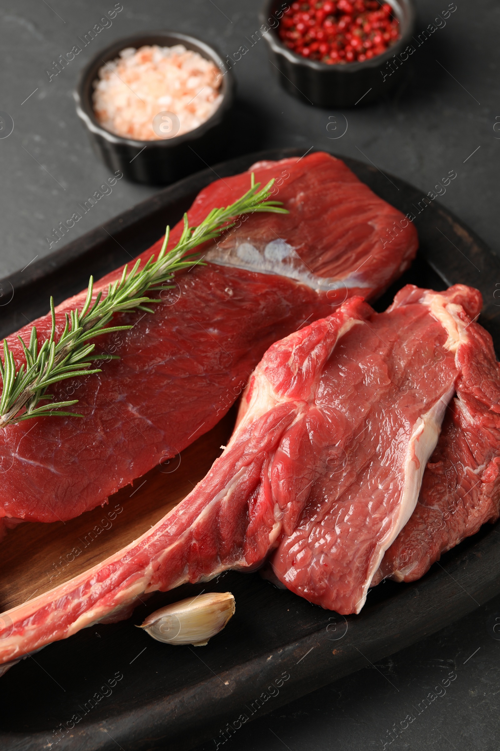 Photo of Pieces of raw beef meat and spices on grey table