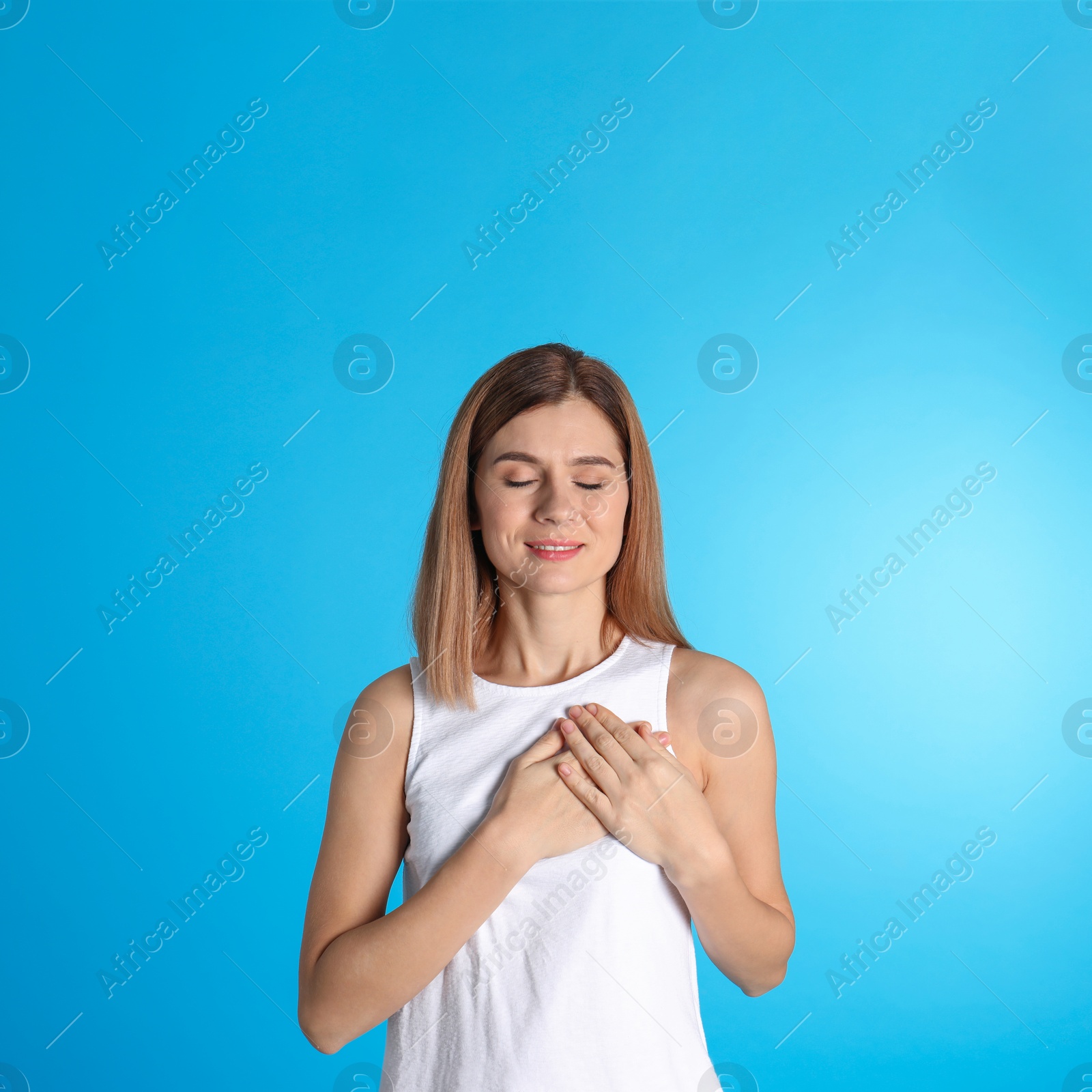 Photo of Portrait of woman holding hands near heart on color background