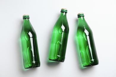 Photo of Glass bottles with water on white background, flat lay