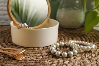 Photo of Stylish jewelry with pearls and box on wicker mat, closeup