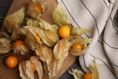 Photo of Ripe physalis fruits with calyxes on wooden table, flat lay