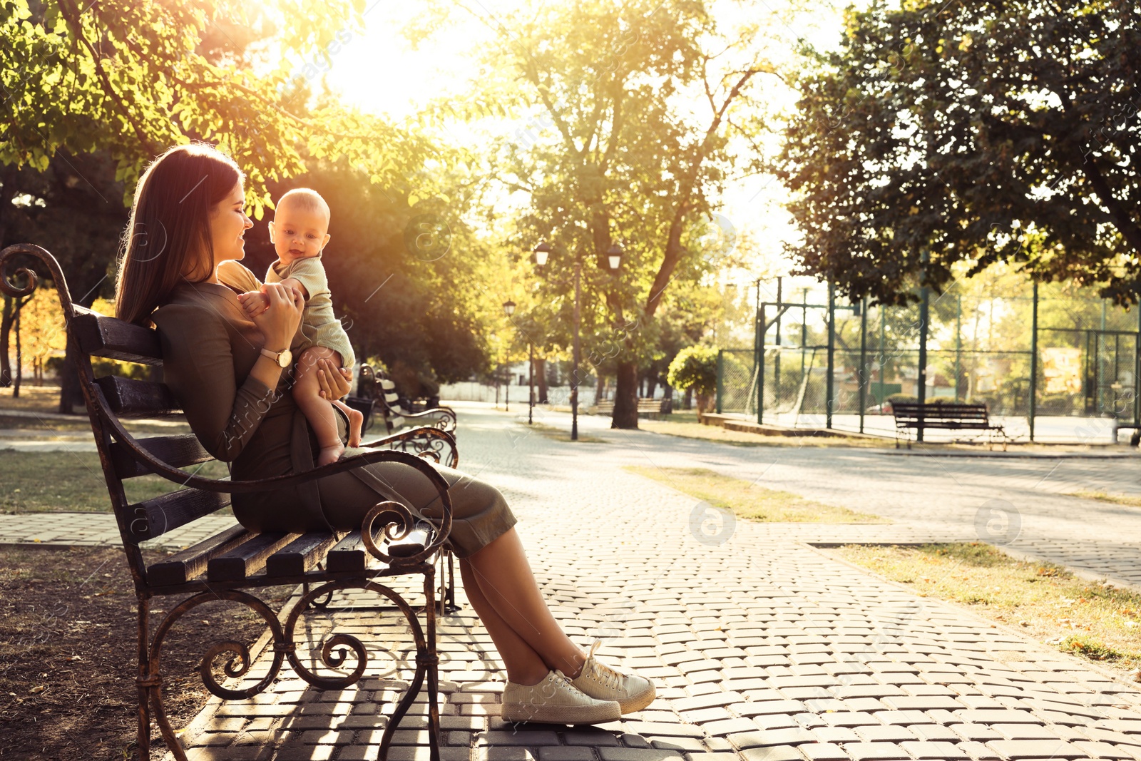 Photo of Young mother with her cute baby on bench in park