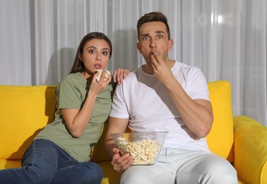 Couple with popcorn watching TV together on couch in living room