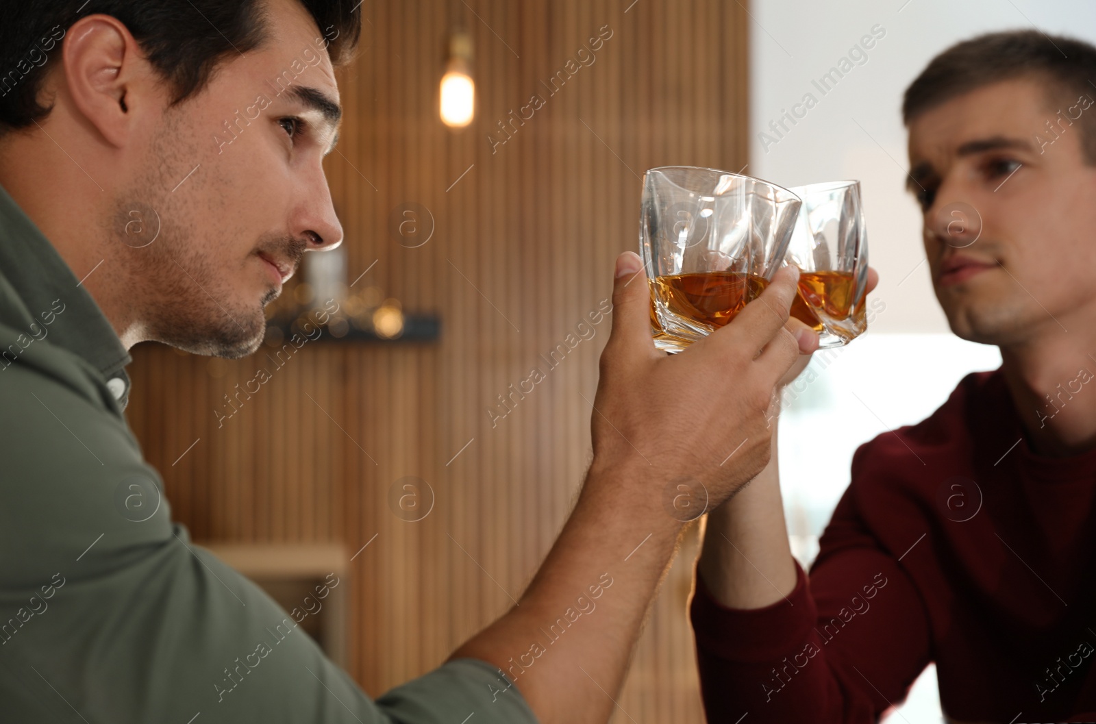 Photo of Young men drinking whiskey together in bar