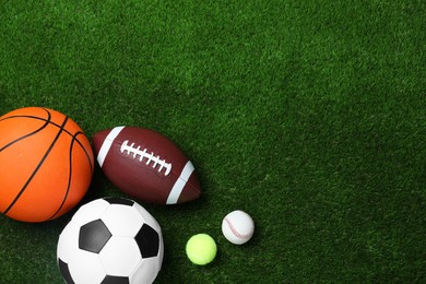 Set of different sport balls on green grass, flat lay. Space for text