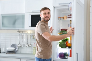 Photo of Man choosing food from refrigerator in kitchen