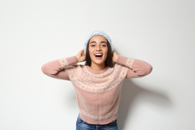 Young woman in warm sweater and knitted hat on white background. Celebrating Christmas