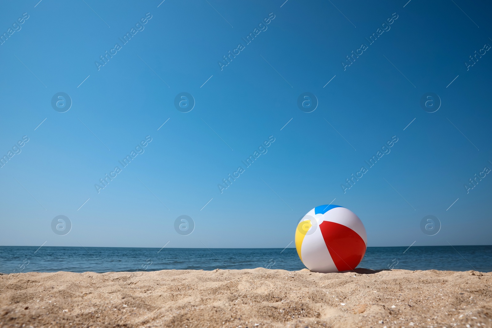 Photo of Colorful inflatable ball on sandy beach. Space for text