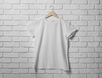 Photo of Hanger with stylish T-shirt on white brick wall