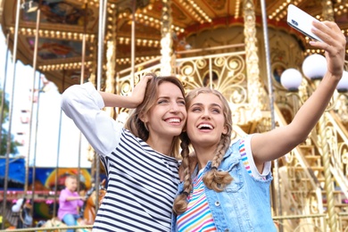 Photo of Attractive women taking selfie in amusement park