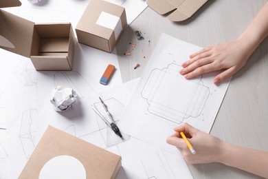 Photo of Woman creating packaging design at light wooden table, top view