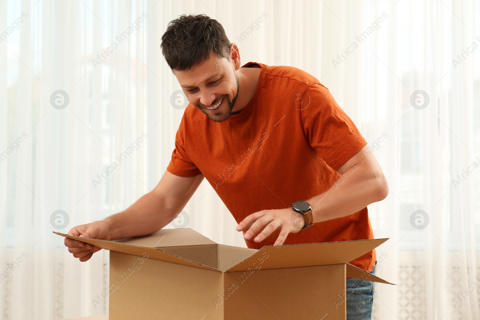 Photo of Happy man opening parcel at home. Internet shopping