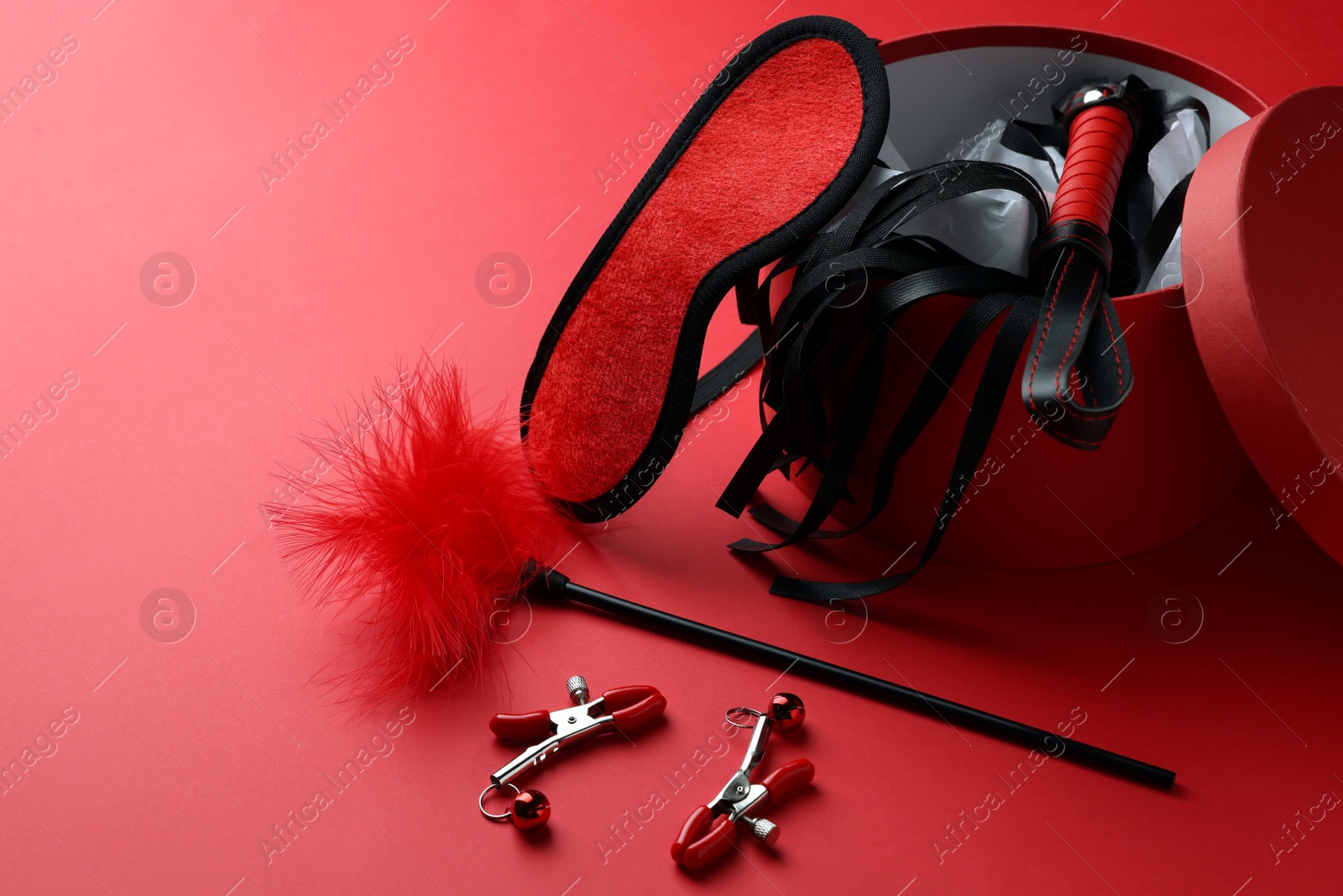 Photo of Gift box with different sex toys on red background. Space for text