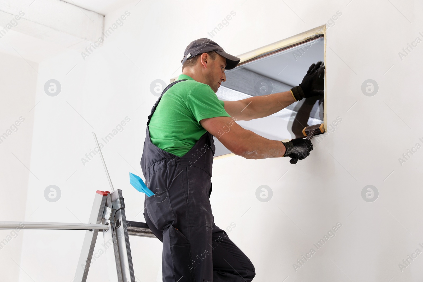 Photo of Worker in uniform installing double glazing window indoors