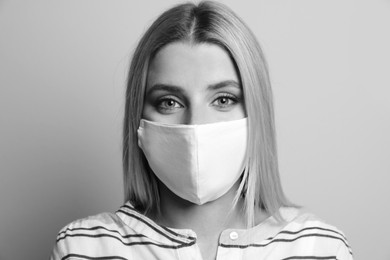 Image of Woman wearing medical face mask on light background. Black and white photography