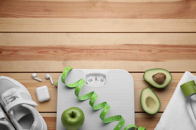 Photo of Flat lay composition with bathroom scale and measuring tape on wooden floor, space for text. Weight loss concept