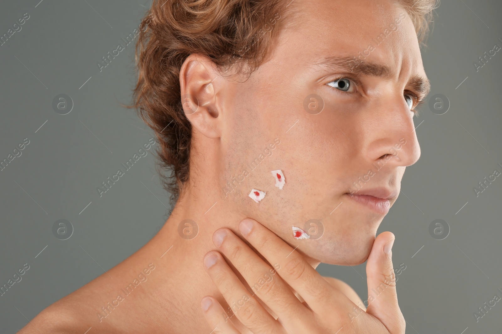 Photo of Young man with face hurt while shaving on gray background