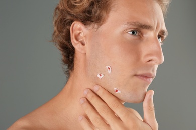 Photo of Young man with face hurt while shaving on gray background