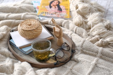 Stylish tray with different interior elements and tea on bed