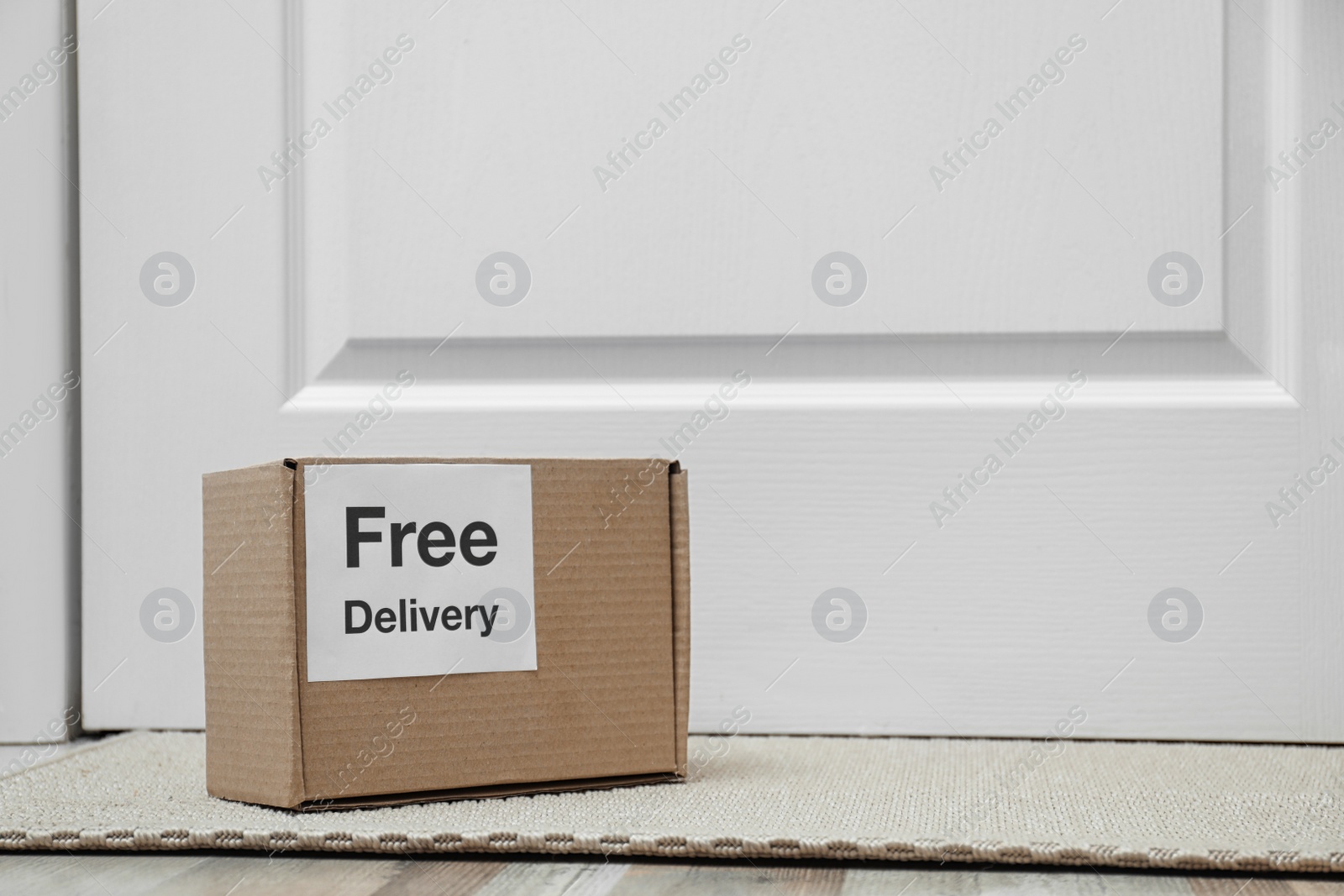 Photo of Parcel with sticker Free Delivery on rug indoors, space for text. Courier service