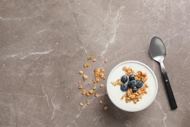 Photo of Bowl with yogurt, berries and granola on gray table, top view