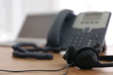 Photo of Headset on wooden table indoors, closeup with space for text. Hotline service