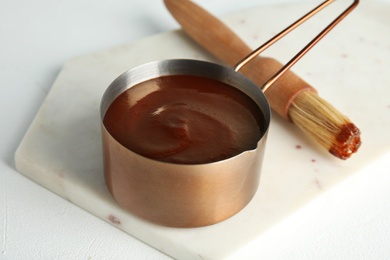 Cooking pot with barbecue sauce and brush on white table