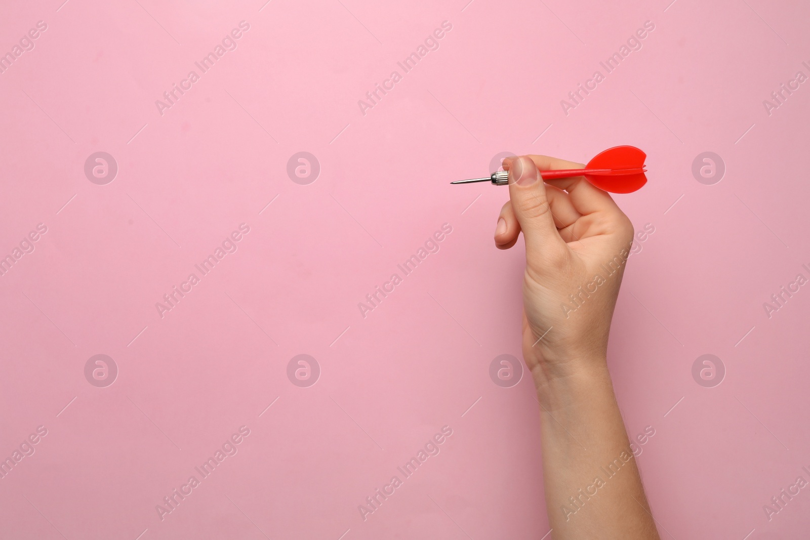 Photo of Woman holding red dart arrow on pink background, closeup with space for text