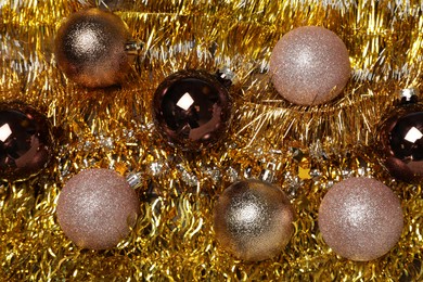 Photo of Many Christmas balls on bright shiny tinsel, top view