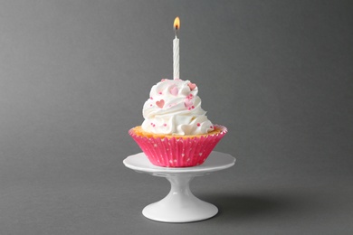 Photo of Delicious cupcake with candle on grey background