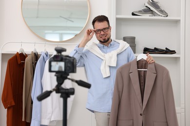 Smiling fashion blogger showing clothes while recording video at home