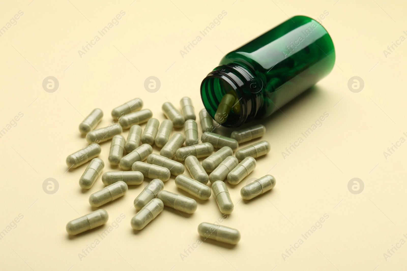 Photo of Vitamin pills and bottle on beige background