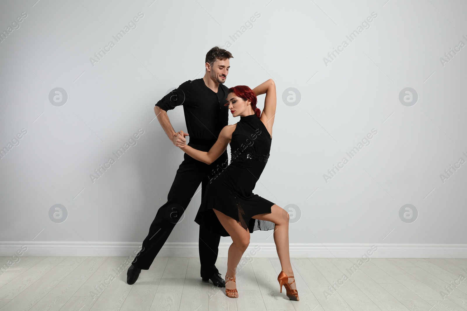 Photo of Beautiful young couple dancing near light wall